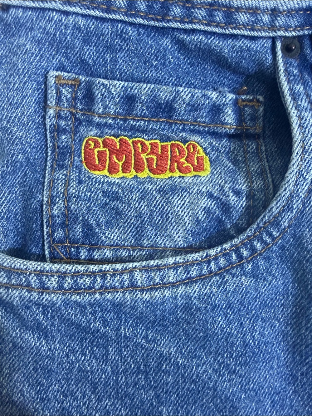 Empyre Blue Denim Jeans with Red and Yellow Logo Patch